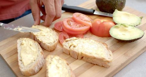 Preparing avocado and tomato sandwich with fresh ingredients