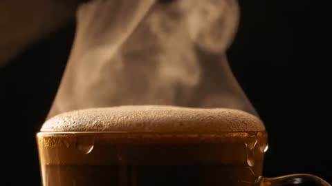 Steam rising from overflowing espresso cup with crema and glistening droplets in slow motion