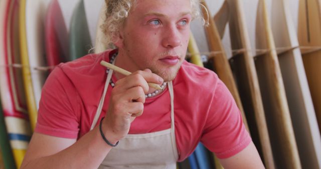 Young male surfboard craftsman contemplating - Download Free Stock Images Pikwizard.com