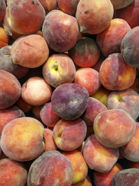 Fresh, vibrant peaches piled together, showcasing natural colors and textures. Ideal for use in health and nutrition visuals, organic and local produce promotions, farmers market advertisements, and culinary blogs or recipe websites.
