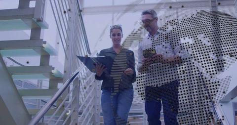 Colleagues Walking Downstairs in Modern Office Atrium with Map Overlay