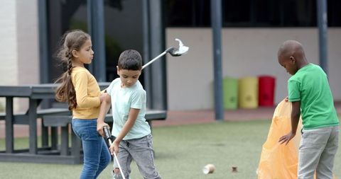 Children Volunteering to Clean Schoolyard with Trash Grabbers