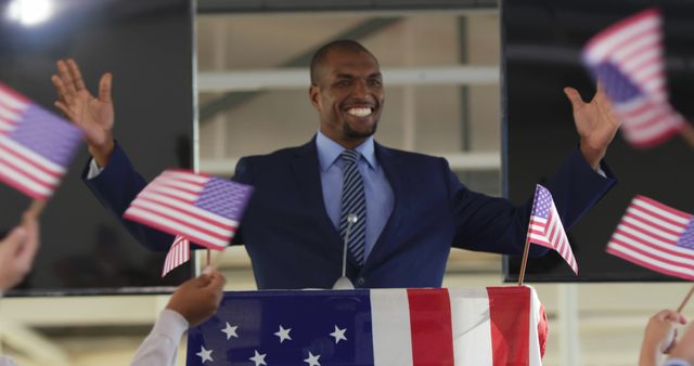 African American politician at a rally, with copy space. He's delivering a speech at a patriotic event with American flags.