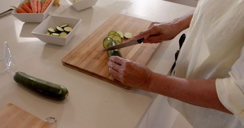 Slicing Fresh Zucchini on Wooden Cutting Board in Modern Kitchen