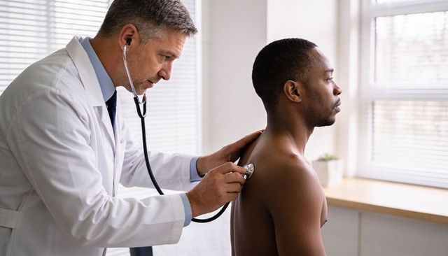 Doctor using stethoscope on shirtless male patient during routine medical checkup