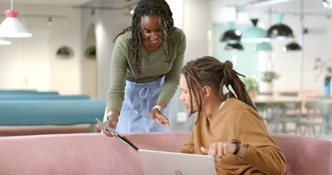 African American Coworkers Collaborating in Modern Office Lounge Sharing Tablet and Laptop