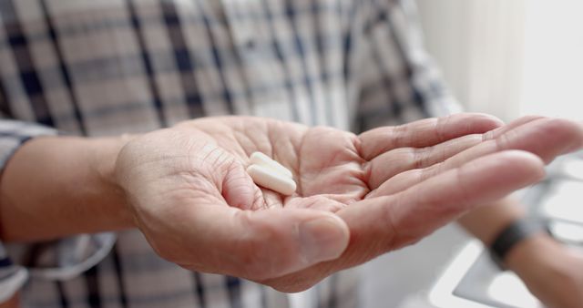 Midsection of senior biracial man at home holding two pills in palm of hand, slow motion - Download Free Stock Photos Pikwizard.com