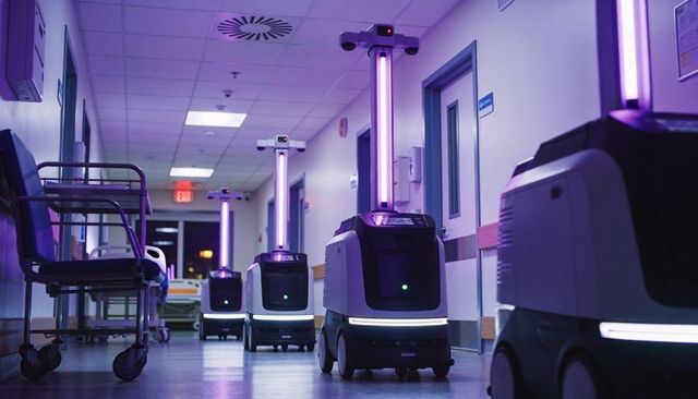 Autonomous uv disinfection robots patrolling hospital corridor emitting purple light