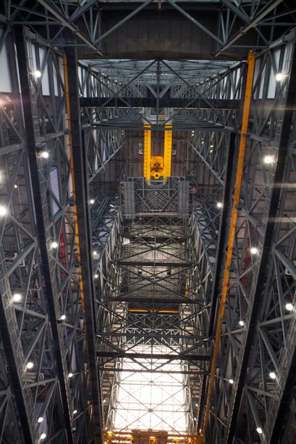 A heavy-lift crane lifts the first half of the B-level work platforms, B south, for NASA’s Space Launch System (SLS) rocket, high up from the transfer aisle floor of the Vehicle Assembly Building (VAB) at NASA’s Kennedy Space Center in Florida. The B platform will be installed on the south side of High Bay 3. The B platforms are the ninth of 10 levels of work platforms that will surround and provide access to the SLS rocket and Orion spacecraft for Exploration Mission 1. The Ground Systems Development and Operations Program is overseeing upgrades and modifications to VAB High Bay 3, including installation of the new work platforms, to prepare for NASA’s Journey to Mars. 