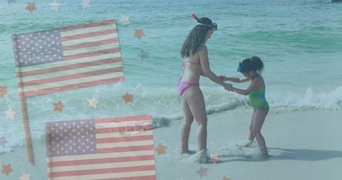 Mother and daughter enjoying beach time with usa flags