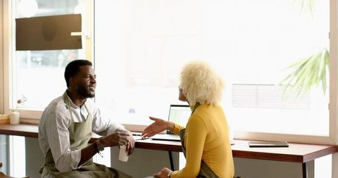 Baristas collaborating at cafe counter with laptop