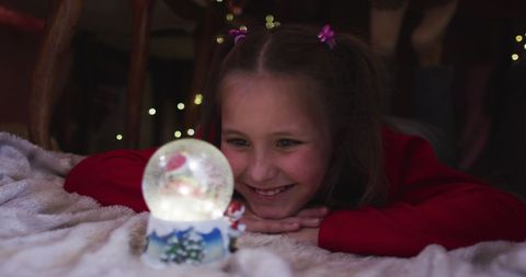 Joyful Girl Admiring Snow Globe in Cozy Blanket Fort