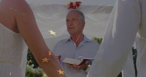 Wedding officiant leading outdoor ceremony amidst romantic decor