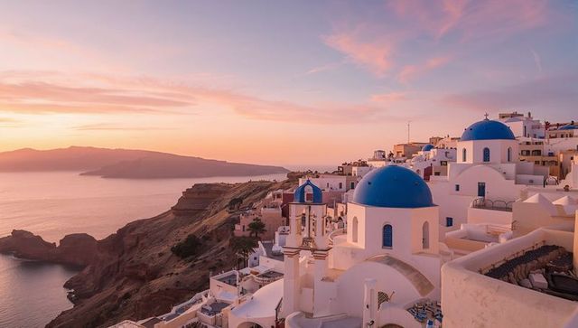 Romantic sunset over iconic greek blue-domed architecture