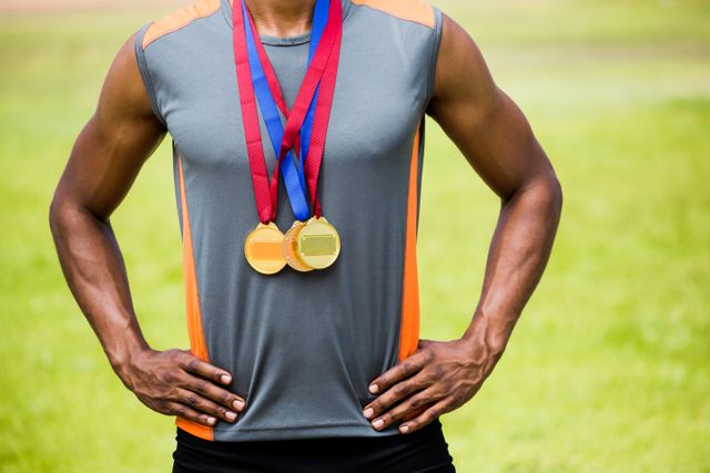 Mid section of athlete posing with gold medals around his neck