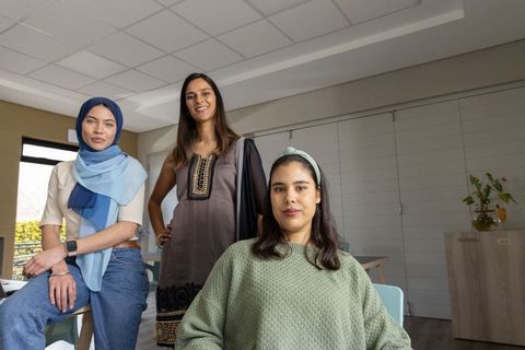 Diverse women posing in modern meeting room showcasing teamwork and inclusive leadership