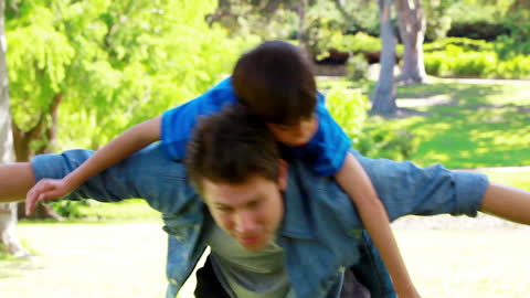 Father Playing Airplane with Son in Sunny Park