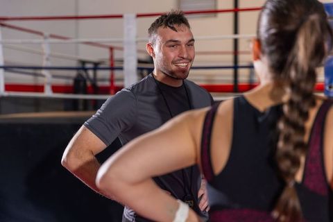 Male coach coaching female boxer in ring smiling during training session