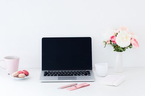 Organized workspace with technology laptop and flowers on white background