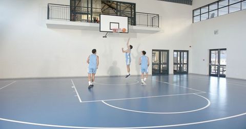 Teenage Male Teammates Playing Basketball in School Gym