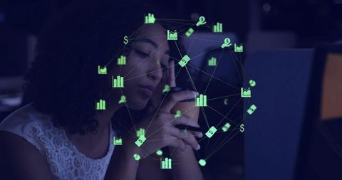 Young woman holding smartphone with finance analytics overlay in dim office workspace
