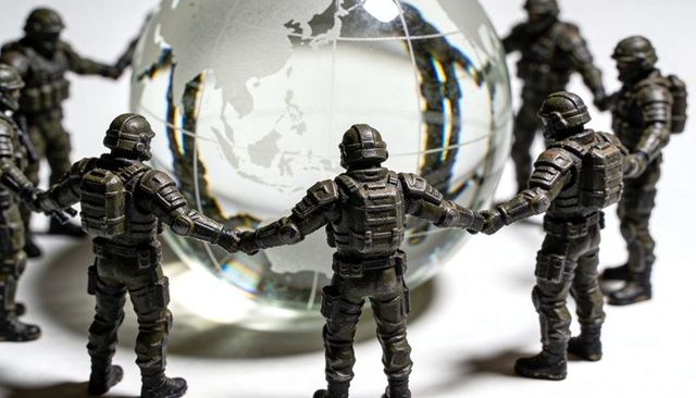 Toy soldiers circling glass globe representing global security and military cooperation