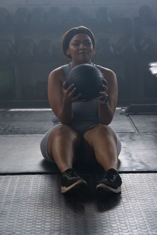African american woman training with medicine ball on gym floor