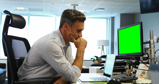 Man Concentrating at Work Desk with Green Screen Monitor - Download Free Stock Images Pikwizard.com