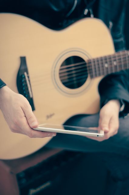 Perfect for articles or blogs about modern musicians, technology in music practice, or tutorials on learning guitar. Could be used for promoting music learning apps, online courses, or tech gadgets for musicians.
