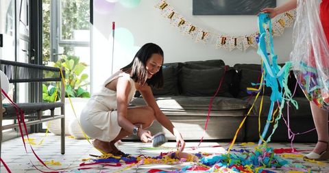 Friends cleaning up after birthday party with streamers