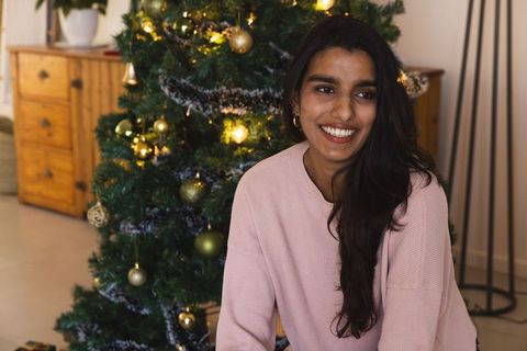 Smiling South Asian Woman by Christmas Tree at Home