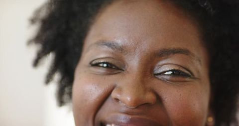 Headshot african american woman smiling with eyes closed natural hair gold stud earring