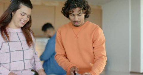 Young adults cooking together at kitchen island chopping vegetables prepping healthy meal