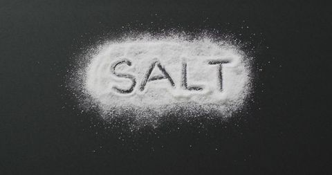 Word 'salt' written in salt on black background for cooking themes