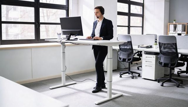 Professional using standing desk and headset in modern open-plan office for remote support