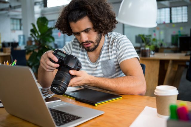 Graphic designer looking at pictures in digital camera at office