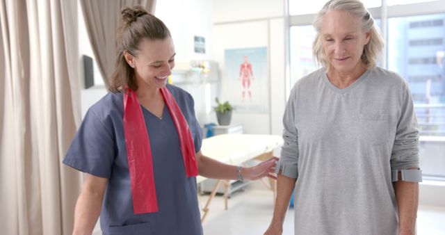 Senior woman participating in a physical therapy session with a nurse guiding her through exercises. Suitable for use in healthcare promotional materials, elder care services, physical therapy training manuals, and rehabilitation programs.