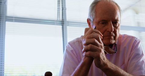 Pensive Elderly Man Contemplating with Glasses in Hand