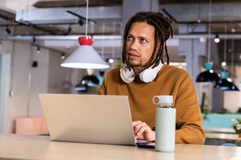 African american professional working on laptop in modern coworking space with headphones