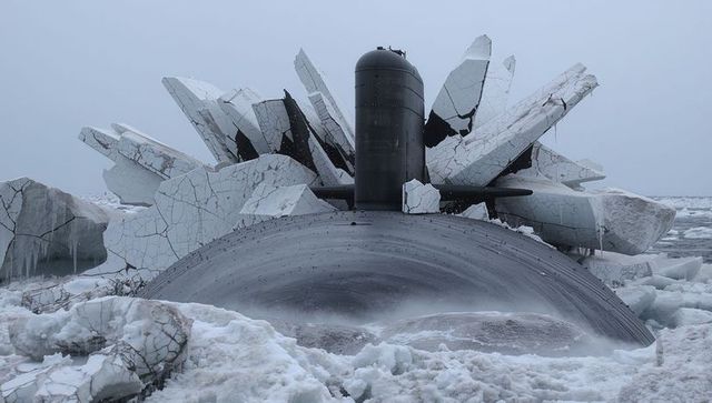 Surfacing military submarine slicing through fractured arctic sea ice with conning tower