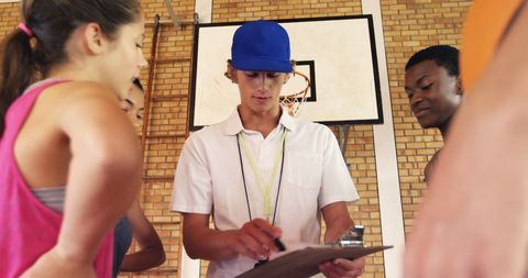 Basketball coach guiding high school students indoors