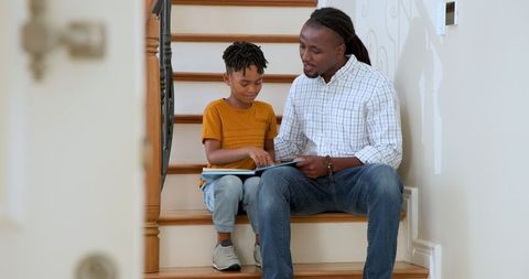Father and Son Bonding Over Storytime at Home on Stairs
