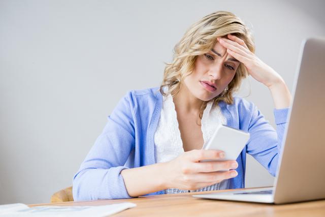 Stressed woman using mobile phone at home