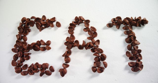 This visually engaging design spells 'EAT' using chocolate cereal pieces, ideal for health and food-related promotional materials. It can be used for blog posts, restaurant menus, social media visuals, and campaign advertisements to draw attention and encourage healthy eating habits.
