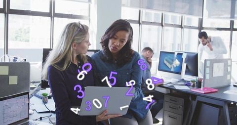 Collaborating over animated numeric data on laptop in modern open-plan office