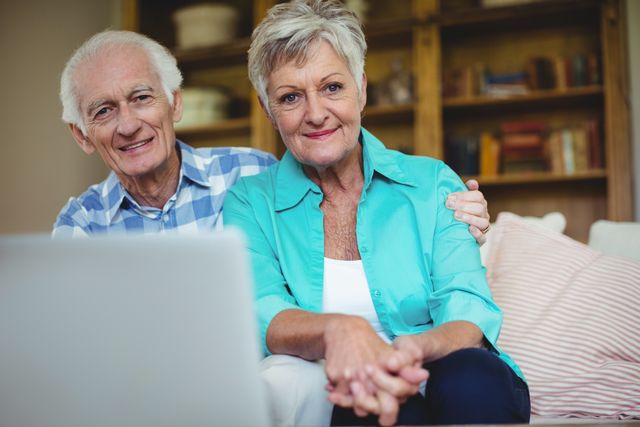 Portrait of senior couple using laptop in living room at home