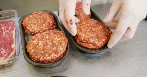 Butcher preparing fresh meat patties in shop