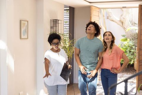 Open house tour guiding young buyers through sunlit entryway with welcoming host