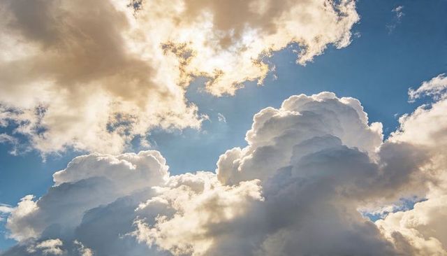 Towering cumulus clouds rising and glowing with sunlit rims over vivid blue sky