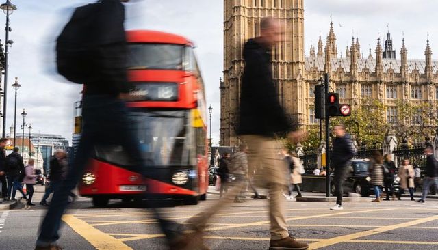 Busy london crossing with red double-decker bus, blurred pedestrians and gothic parliament